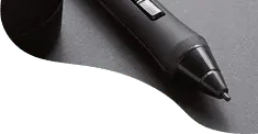 A close-up of a black digital drawing pen on a grey and green background.