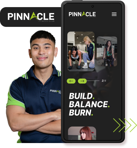 A man in a Pinnacle Fitness Club shirt stands next to a large smartphone displaying the club's app, featuring images of people working out and the text "Build. Balance. Burn." Consider how you can revamp your website to have such an engaging feature, driving more members to your fitness community.