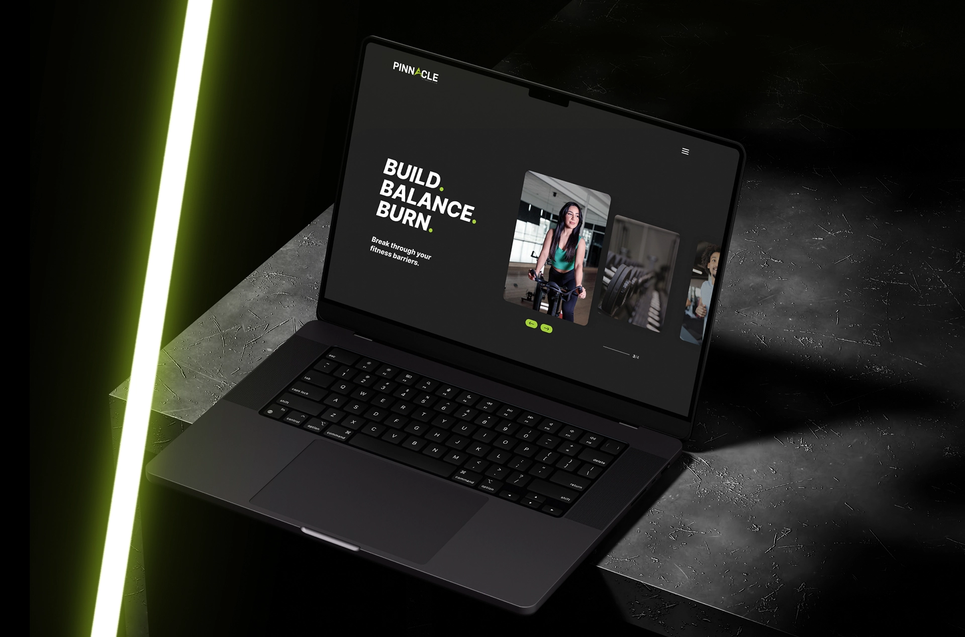 A laptop screen displays a fitness website titled "Pinnacle" with the text "Build. Balance. Burn." and shows a woman exercising. The laptop rests on a dark surface illuminated by green light streaks, capturing the essence of peak performance.