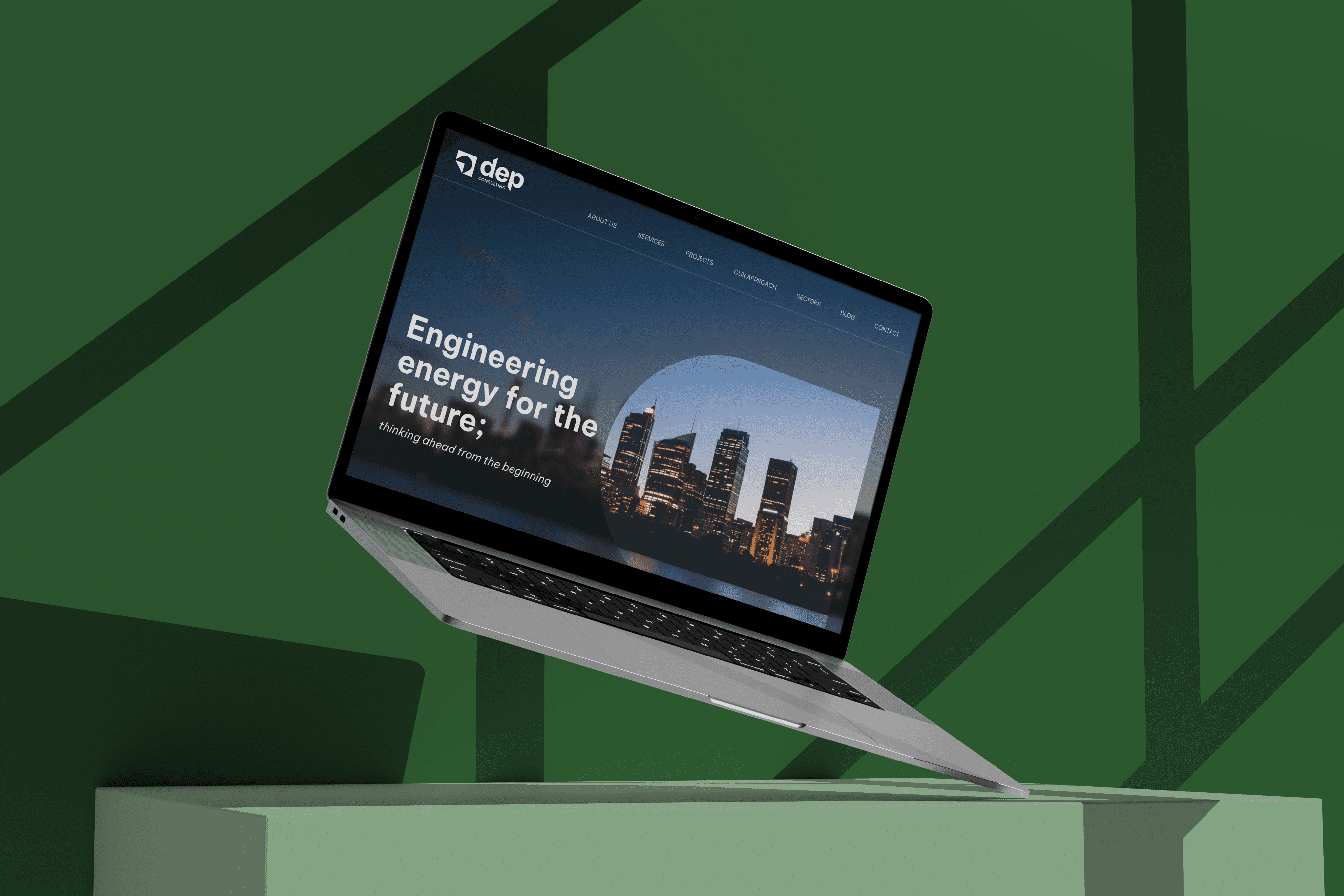 Laptop on a green stand displaying a corporate website with a city skyline at night, captioned "engineering energy for the future.